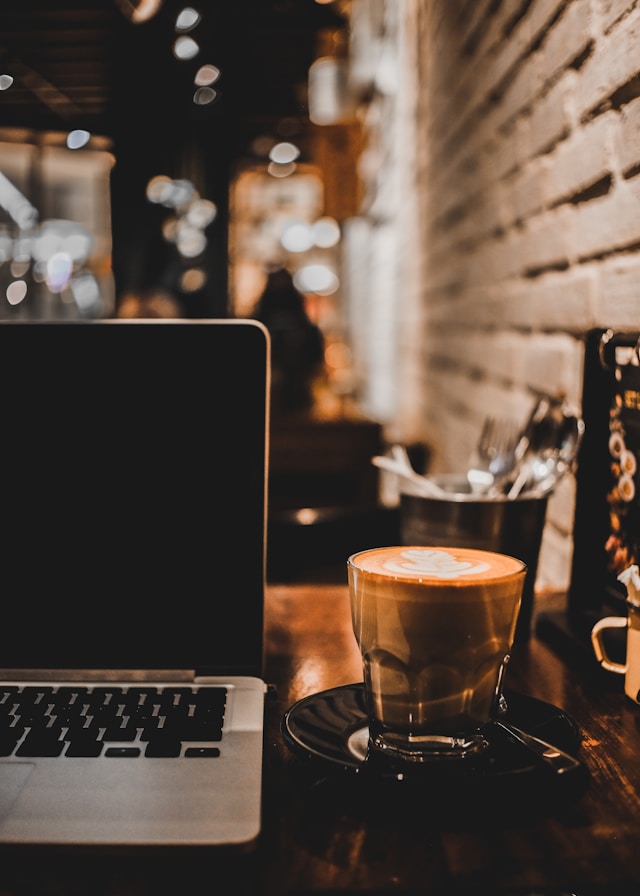 A cup of coffee beside a laptop on a café table